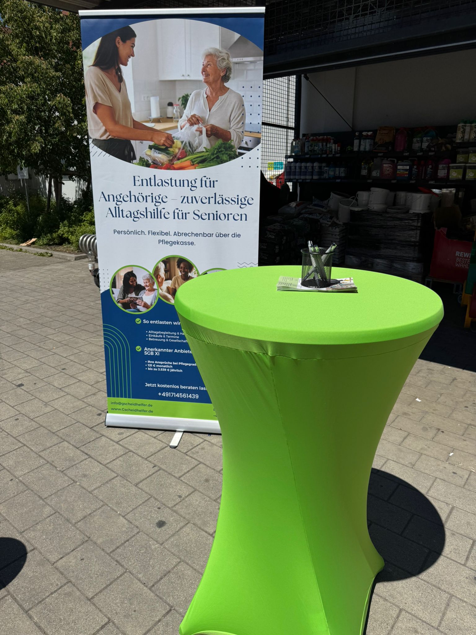 Informationsstand von Gscheidhelfer mit Roll-Up Banner und grünem Stehtisch bei REWE Türkheim